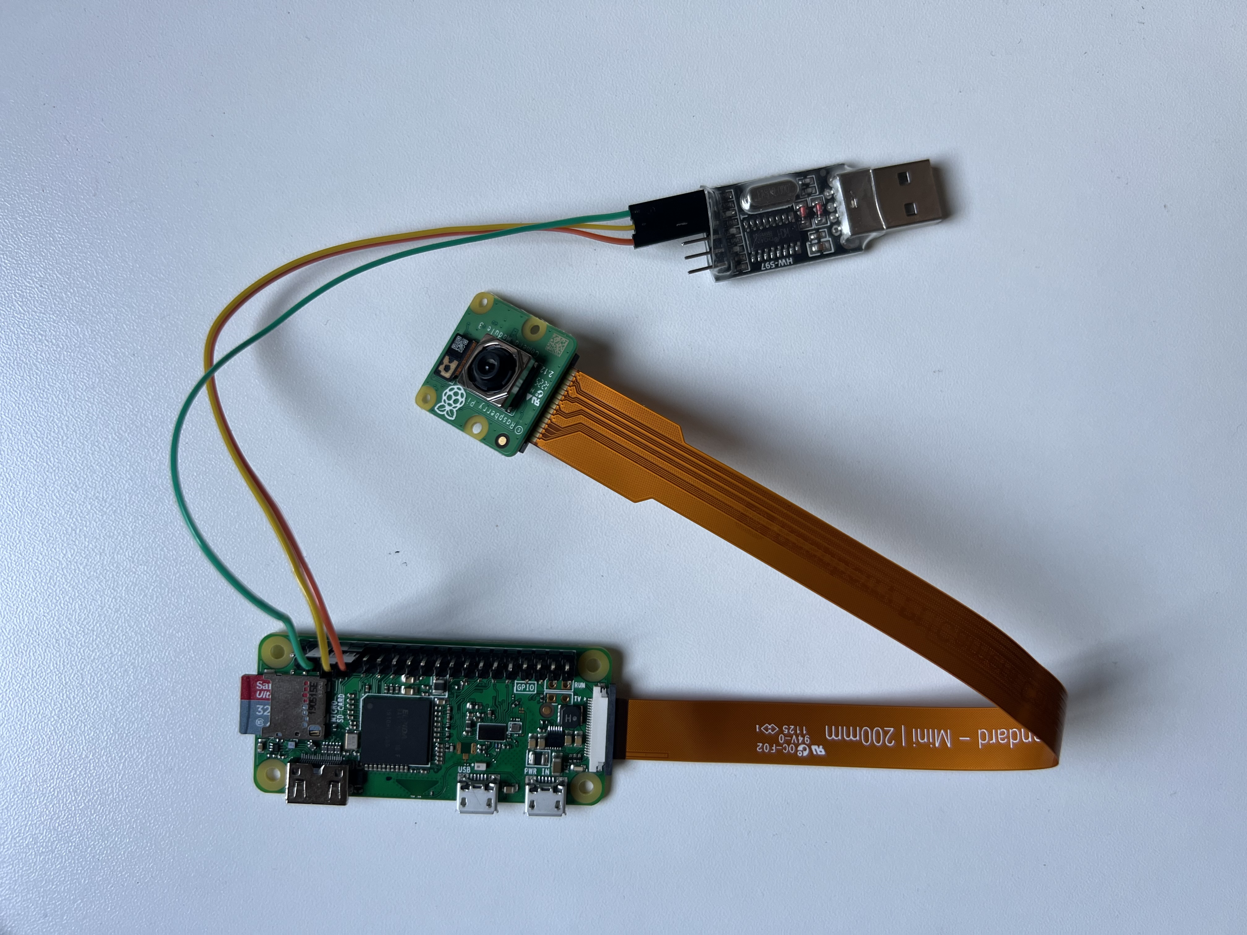 photo of raspberry pi 0 w connected to camera module v3 and usb to ttl adapter.
