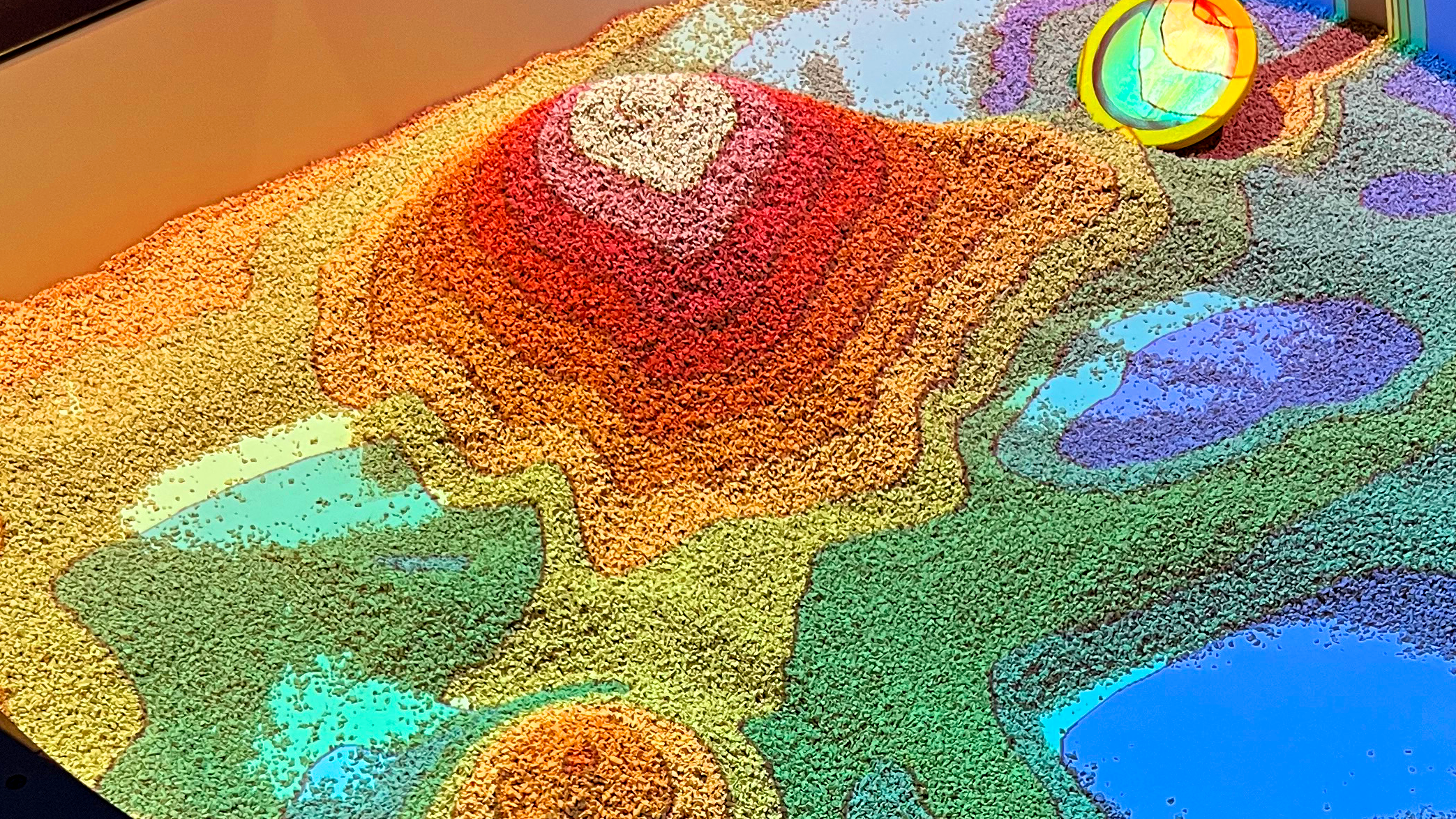 augmented reality sandbox with projected depth mapped data onto the sand in the box. coordinating colors cover the different heights of sand.